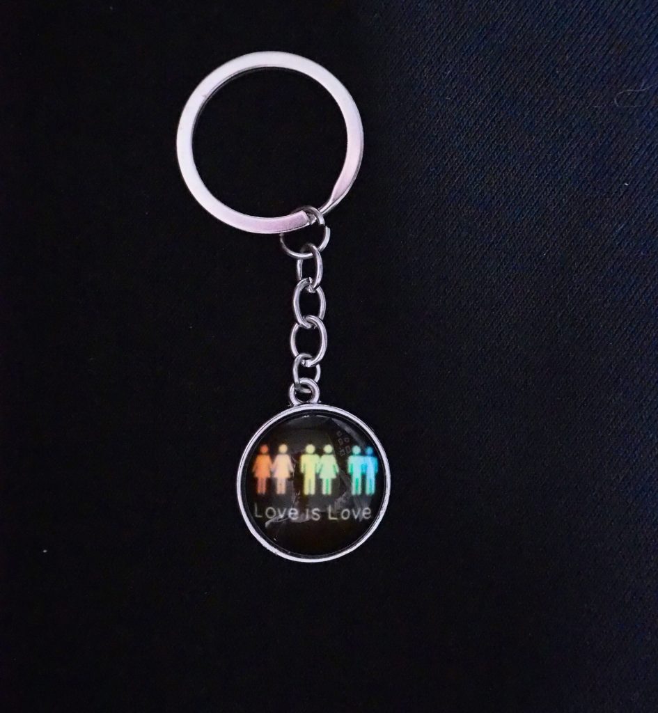 Rund nøkkelring med symboler og teksten LOVE IS LOVE
